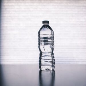 Stylish photo of a clear plastic water bottle on a reflective surface with a soft shadow.